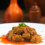 rendang in the white plate on wooden tray with vas and guci background